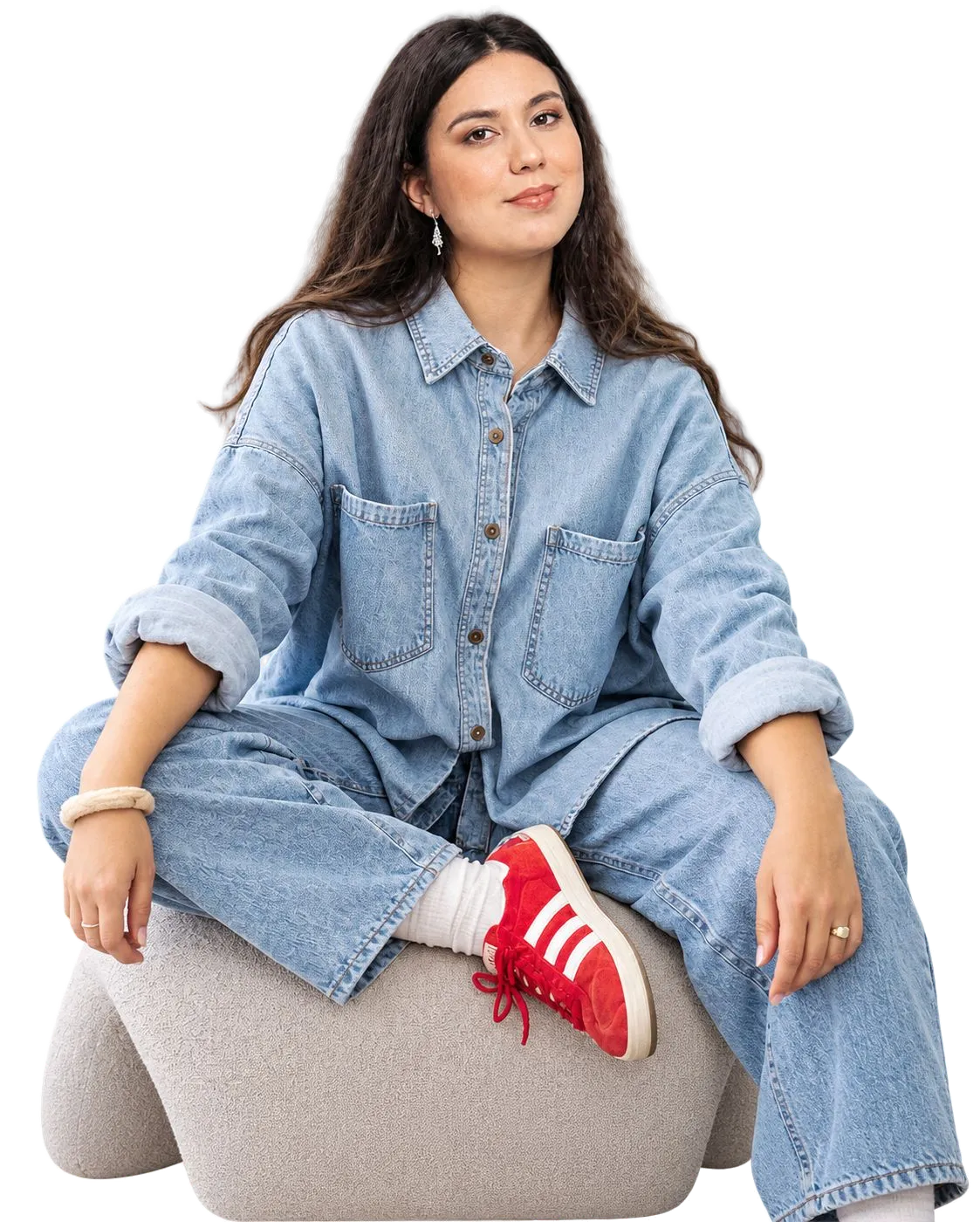 Catalina Taune sonriendo, con ropa vaquera y zapatillas rojas, sentada en un puf